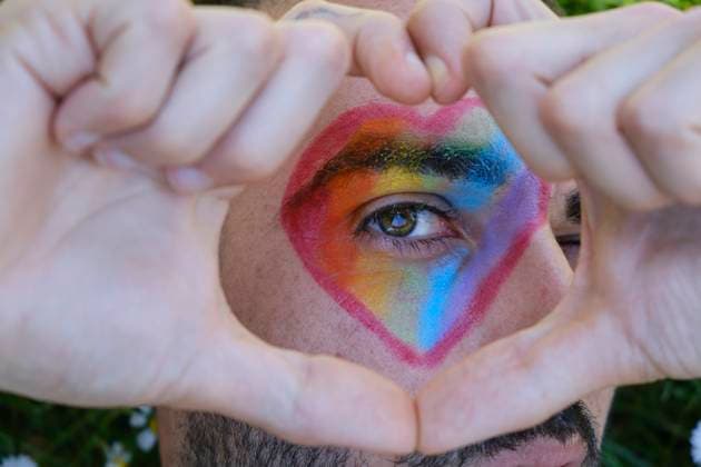 Creative Highlights Symbolbilder gay man with green eyes and beard lying on a lawn full of daisies, with a heart painted on his eye in the colors of the lgtb flag. pride Barcelona, CT, Spain R_ZCUGHF210518-749083-01 ,model released, Symbolfoto
