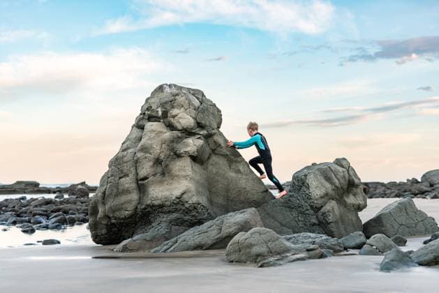Creative Highlights Symbolbilder Child climbing rocks on beach Ocean Beach, Hawke s Bay, New Zealand CR_JUCR241229-1616658-01 ,model released, Symbolfoto