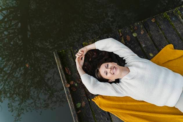 Creative Highlights Symbolbilder Smiling woman lying on pier near lake model released, Symbolfoto, NDEF02098