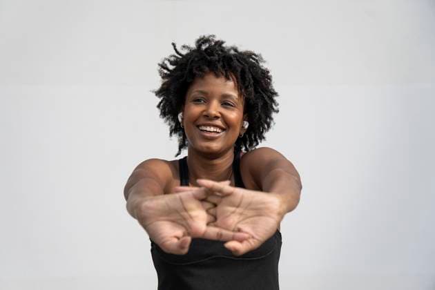 Creative Highlights Symbolbilder Smiling woman stretching arms against gray background model released, Symbolfoto, PNAF06664