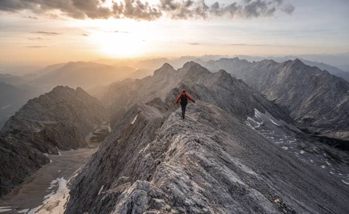 Bergsteiger mit Helm auf einem schmalen felsigen Berggrat bei Sonnenaufgang, Überschreitung des Jubiläumsgrat, Ausblick auf Höllental mit Höllentalferner und Alpspitze, Wettersteingebirge, Bayern, Deutschland, Europa Mountaineer with helmet on a narrow rocky ridge at sunrise, crossing the Jubiläumsgrat, view of Höllental with Höllentalferner and Alpspitze, Wetterstein range, Bavaria, Germany, Europe Copyright: imageBROKER MaraxBrandl ibxmab11955251.jpg ,model released, Symbolfoto ,property released