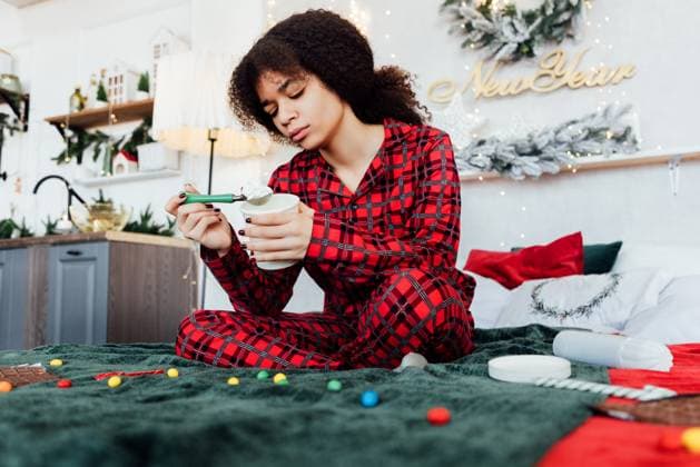 Creative Highlights Symbolbilder Junge, verärgerte afrikanische Frau sitzt auf dem Bett und isst Eiscreme. Unglückliches schwarzes Mädchen im Schlafanzug ist traurig am Weihnachtsabend. Süßigkeiten auf Decke und Neujahrsdekoration. Young upset African woman is sitting on bed and eating ice cream. Unfortunate black girl in pajamas is sad on Christmas Eve. Sweets on blanket and New Year decorations. Depression. Stress eating ,model released, Symbolfoto Copyright: xZoonar.com DashaxPetrenkox 22584658 ,model released, Symbolfoto ,property released