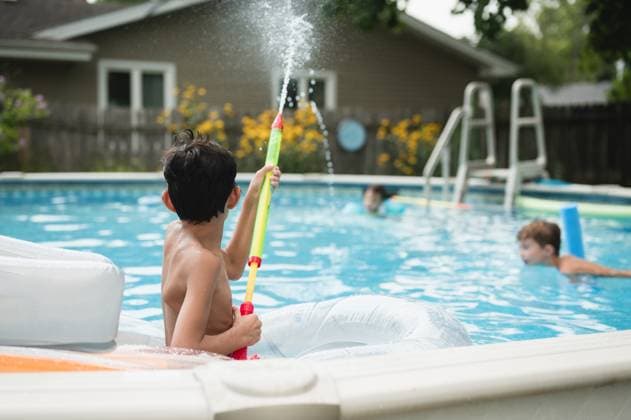IMAGO Creative, Sommer, Sommertage im Garten IMAGO Creative, Jahreszeit Sommer, Sommerferien Backview of child spraying water toy in pool with other kids swimming Chicago, Illinois, United States CR_AKAO250103-1506409-01 ,model released, Symbolfoto
