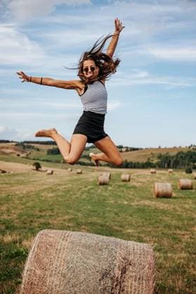 Creative Highlights Symbolbilder Young woman jumping joyfully over hay bales in a sunny field, showcasing freedom and happiness. 27500862 ,model released, Symbolfoto RECORD DATE NOT STATED