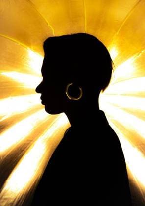 Creative Highlights Symbolbilder Silhouette of a person with hoop earrings against a radiant yellow light background. 28318466 ,model released, Symbolfoto RECORD DATE NOT STATED