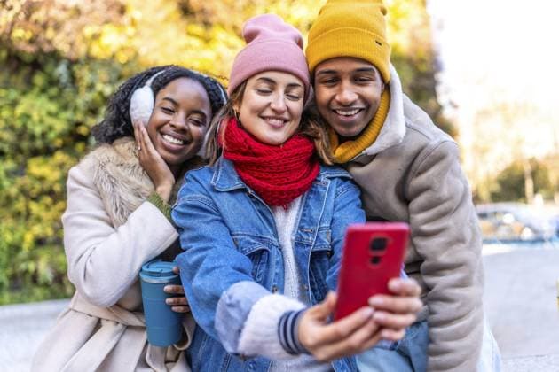 IMAGO Creative, Winter, In der Stadt Multirassische junge Freunde, die zusammen Spaß haben und ein Selfie mit Smartphone in einer winterlichen Stadtumgebung machen Multiracial young friends having fun together taking a selfie with smartphone in a winter city environment Copyright: imageBROKER UnaixHuizi ibxuhu12061577.jpg ,model released, Symbolfoto ,property released