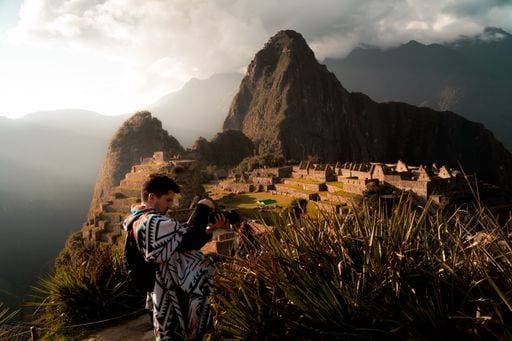 Creative Highlights Symbolbilder A photographer capturing the breathtaking view of Machu Picchu in Peru during sunset with a mountain backdrop. 26115065 ,model released, Symbolfoto RECORD DATE NOT STATED