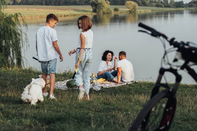 Middle Aged Man and Woman Having Picnic While Their Two Teenage Children, Son and Daughter Playing with Pet Dog, Happy Four Members Family Enjoying Weekend Outdoors by Lake, model released, , 47286172.jpg, family, four members, mother, father, woman, man, middle aged, children, teenage, daughter, son, kids, happy, parents, childhood, parenthood, together, girl, boy, female, male, pet, dog, west highland white terrier, lake, river, water, bicycle, picnic, outdoors RECORD DATE NOT STATED