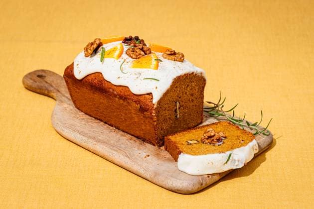 A freshly baked carrot cake loaf topped with cream cheese frosting, garnished with walnuts and rosemary Set on a wooden board against a yellow linen backdrop Model Released CintiaViudez_ID25764_744160_009 Copyright: xCintiaxViudezx RECORD DATE NOT STATED