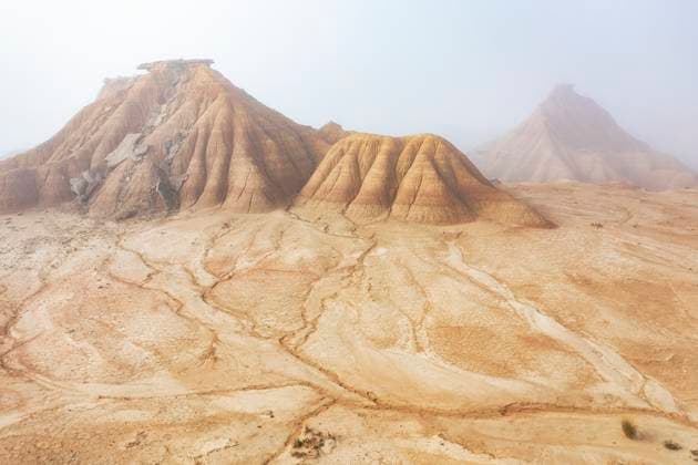 Creative Highlights World A serene desert landscape features eroded hills cloaked in a soft mist The golden earth and intricate rock formations create a sense of mystery and solitude Model Released DavidJerez_ID25774_744470_035 Copyright: xDavidxJerezx