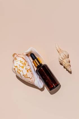 IMAGO Creative, Naturkosmetik An amber dropper bottle is artistically placed alongside two seashells on a beige background The arrangement highlights a natural, minimalist skincare theme Model Released MarinaMos_ID25391_733999_007 Copyright: xMarinaxMosx RECORD DATE NOT STATED