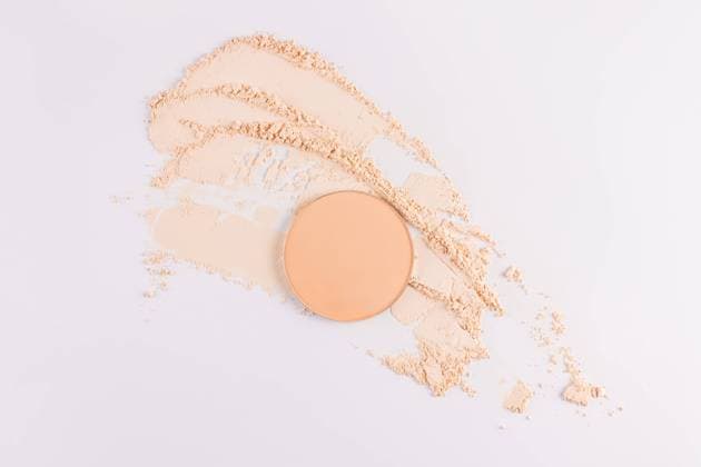 IMAGO Creative, Naturkosmetik Top view of a circular compact powder alongside scattered loose face powder on a clean, white background. Ideal for depicting cosmetics and beauty products. Model Released MarinaMos_ID25841_746425_003 Copyright: xMarinaxMosx