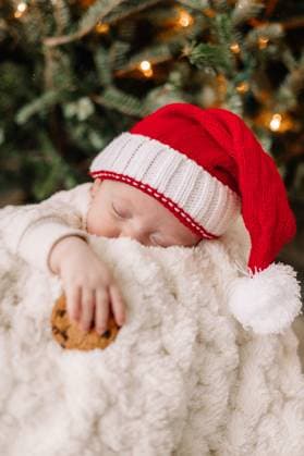 Baby sleeping with Santa hat holding cookie under Christmas tree. Pittsburgh, Pennsylvania, United States CR_QIWH250110Y-1624294-01 ,model released, Symbolfoto