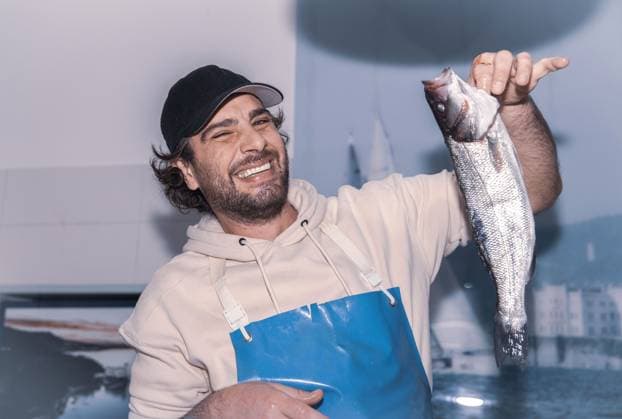 Creative Highlights Symbolbilder Caucasian male adult fisherman smiling holding fresh fish in blu Villach, Carinthia, Austria R_GVYI250114-1628243-01 ,model released, Symbolfoto