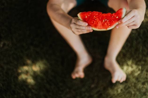 Child sitting barefoot in grass holding watermelon Tulsa, Oklahoma, United States CR_KRRY250117-1630510-01 ,model released, Symbolfoto