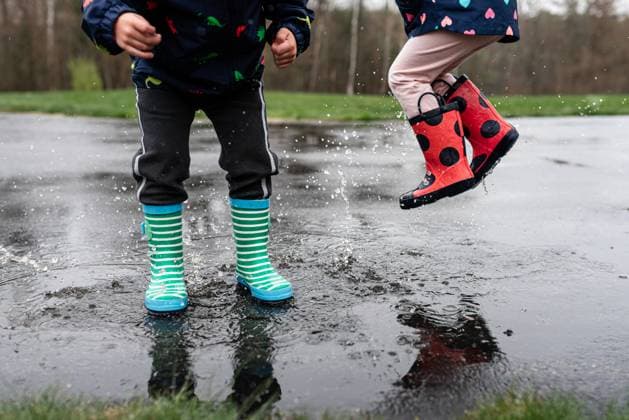 Children in colorful rain boots splashing in a puddle outdoors. Epping, New Hampshire, United States R_MJOR250120A-1636629-01