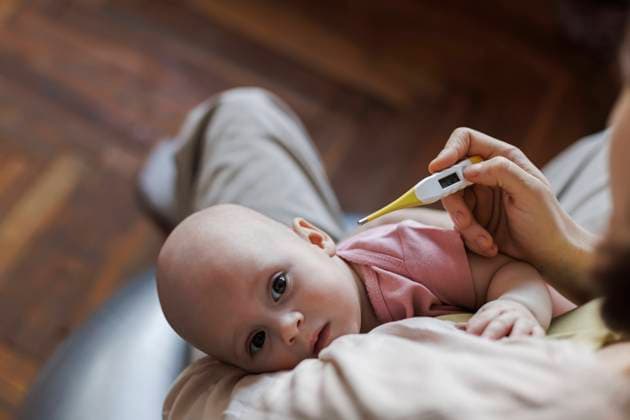 Mother holding baby and checking fever with thermometer at home model released, Symbolfoto property released, LLUF01142
