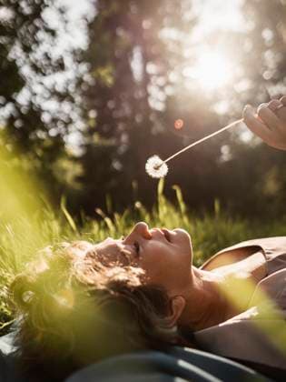 Mature woman holding flower and lying down in public park model released, Symbolfoto, IEF00823