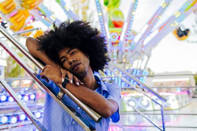 Young Afro man leaning on railing at amusement park model released, Symbolfoto, ALZF00829