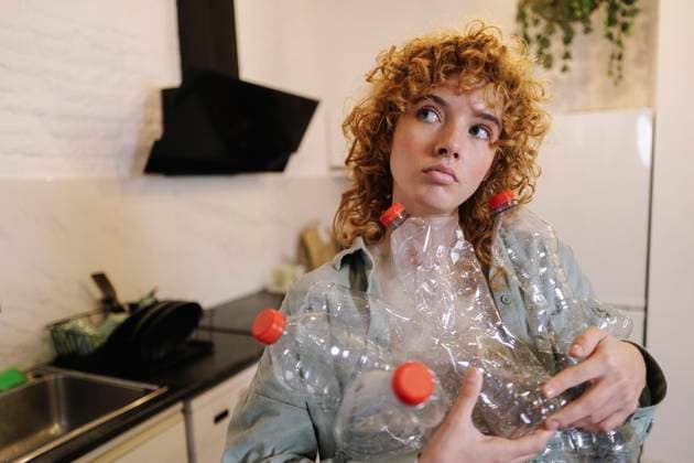 IMAGO Creative, Frühling, Frühjahrsputz Thoughtful woman holding used plastic bottles at home model released, Symbolfoto property released, ASGF06023