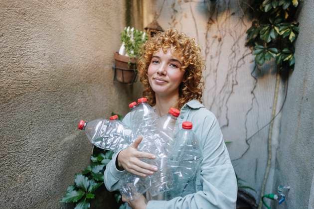 Smiling woman holding used plastic bottles in alley model released, Symbolfoto property released, ASGF06037
