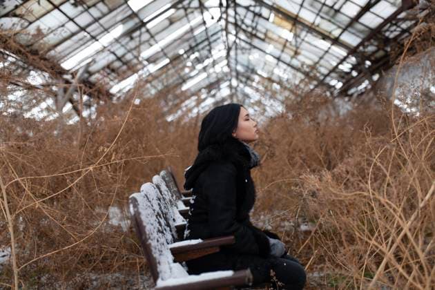 Contemplative woman sitting on chair amidst dried plants in old greenhouse model released, Symbolfoto, VCF00572