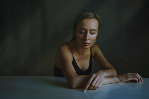 Woman with eyes closed sitting at table model released, Symbolfoto, AZF00623