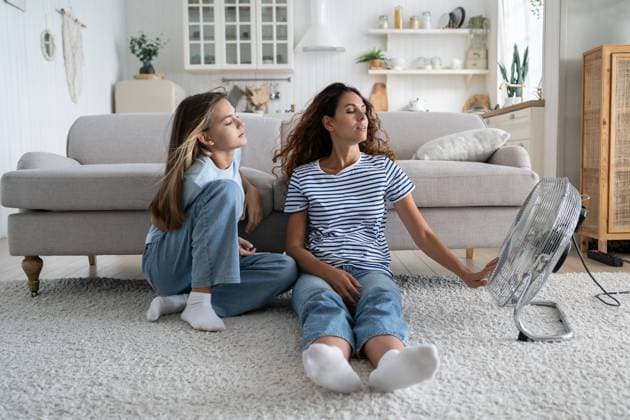 IMAGO Creative, Jahreszeit Sommer, Hitze Liebevolle sorglose Frau Mutter und Teenager-Mädchen sitzt in entspannter Position auf dem Boden im Wohnzimmer in der Nähe von Fan Loving carefree mother and teenage girl sits in relaxed position on floor in living room near fan. Satisfied positive family of woman and daughter spend time at home during abnormally high temperature ,model released, Symbolfoto Copyright: xZoonar.com DmitriixMarchenkox 22675996 ,model released, Symbolfoto ,property released