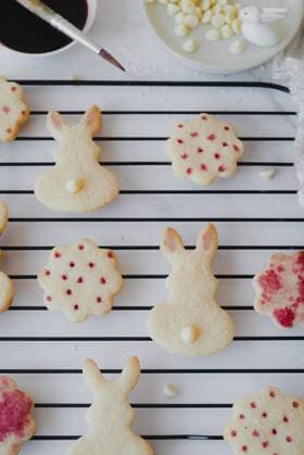 Top view of Easter bunny-shaped cookies delicately painted with hibiscus tea on a cooling rack. The image captures the intricate details of the natural pink hues decorating each cookie. Model Released CamilaMacedo_ID26013_750676_005 Copyright: xCamilaxMacedox RECORD DATE NOT STATED