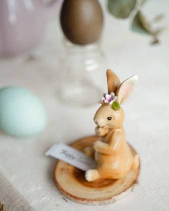 A charming Easter rabbit figurine adorned with delicate flowers sits next to naturally dyed eggs. Model Released CamilaMacedo_ID26016_750689_003 Copyright: xCamilaxMacedox RECORD DATE NOT STATED