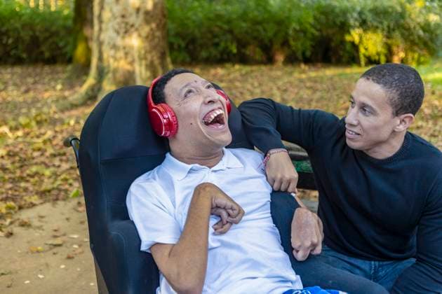 Spanish Cameroonian siblings share a joyful outdoor moment at a park. One sibling, wearing headphones, has cerebral palsy, highlighting the family s mixed race bond. Model Released JuanAizpuru_ID26079_752147_016 Copyright: xJuanxAizpurux