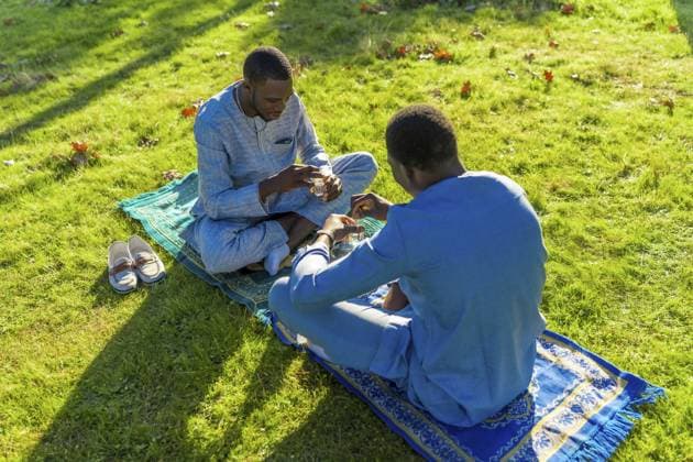 Zwei senegalesische Männer in traditioneller Dashiki Kleidung trinken gemeinsam Tee auf einem Gebetsteppich in einem lebhaften grünen Park Two senegalese men in traditional dashiki clothing are enjoying tea together on a prayer rug in a vibrant green park Copyright: imageBROKER UnaixHuizi ibxuhu12161925.jpg ,model released, Symbolfoto ,property released