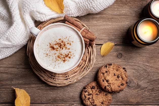Gemütlicher Herbsthintergrund, Kaffee und Kerzen Autumn cozy composition. Cup of cappuccino coffee, chocolate chip cookies, burning candles and yellow autumn leaves on wooden background, top view. Hygge comfortable concept flat lay. Copyright: xZoonar.com OksanaxBratanovax 22704170