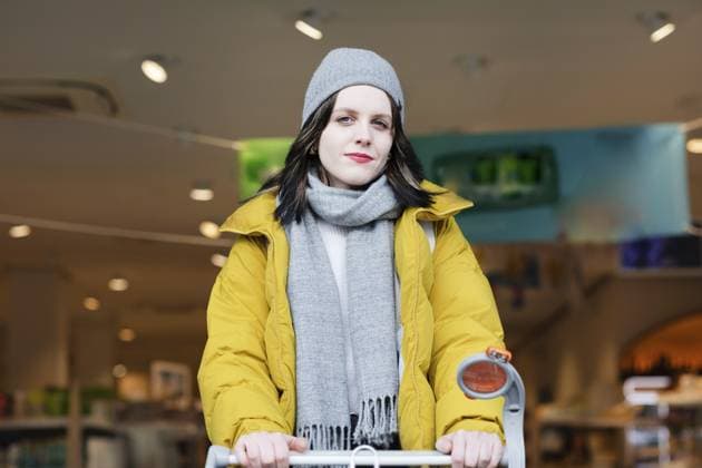 Frau in gelber Jacke schiebt Einkaufswagen in Geschäft zu Fuß, Mobilität, Umweltschutz Woman in yellow jacket pushes shopping trolley into shop on foot, Mobility, Environmental protection Copyright: imageBROKER SigridxGombert ibxsig12280082.jpg ,model released, Symbolfoto ,property released