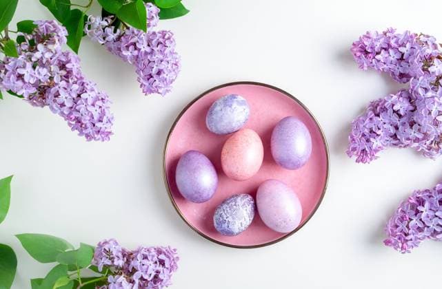 Ostereier liegen auf einem Teller, umrahmt von blühenden Fliederzweigen Close-up top view of beautiful nacreous pink and lilac easter eggs lie on a pink plate framed by flowering branches of lilac on a white background. Selective focus. Copyright: xZoonar.com OlgaxGubskayax 22729183