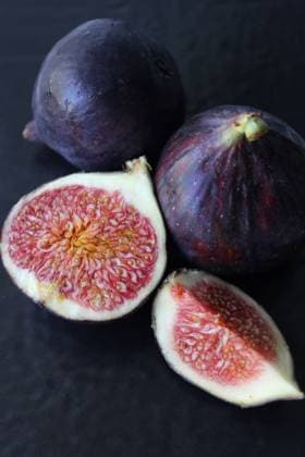 Frische Feigen mit leuchtend rotem Inneren auf dunklem Hintergrund Ripe figs, whole and cut, showcasing their vibrant red interior and seeds against a dark backdrop Copyright: xZoonar.com IharxIvanouskix 22743174