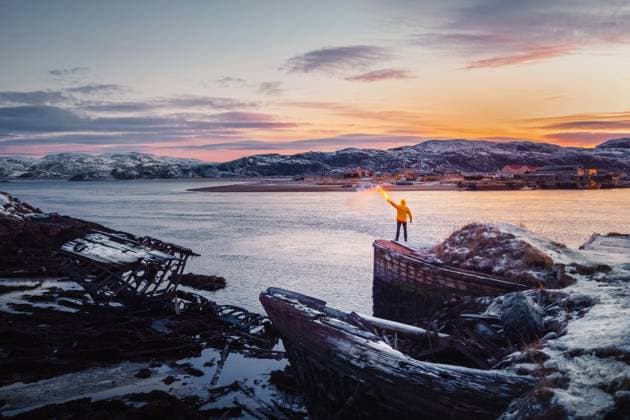 Eine gelbe Figur mit einem Feuerschein. Friedhof der Schiffe, Winter Sonnenuntergang Blick in einem alten Fischerdorf am Ufer der Barentssee, der Kola-Halbinsel, Teriberka A yellow figure with a signal light. Graveyard of ships, winter sunset view in an old fishing village on the shore of the Barents sea, the Kola Peninsula, Teriberka, Russia. ,model released, Symbolfoto Copyright: xZoonar.com StanislavxSablinx 22752504 ,model released, Symbolfoto ,property released