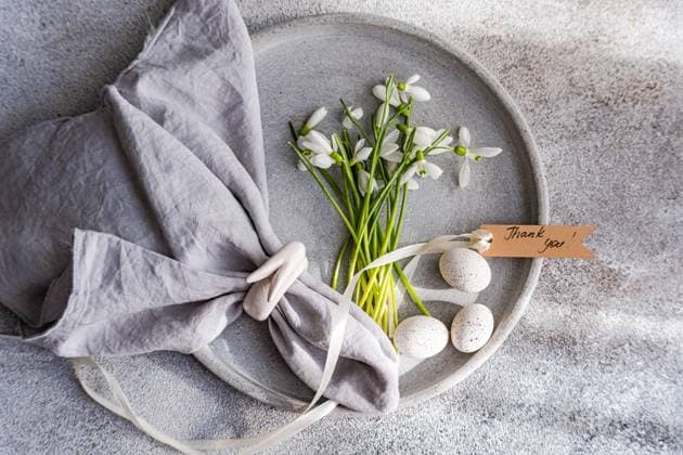 IMAGO Creative, Ostern, Bräuche, Osterbrunch Top view of an exquisite spring table setting featuring fresh snowdrops arranged on a gray ceramic plate, complemented by a gray linen napkin, delicate quail eggs, and a Thank you! tag, all laid on a textured surface. Model Released AnnaBogush_ID26489_764291_002 Copyright: xAnnaxBogushx