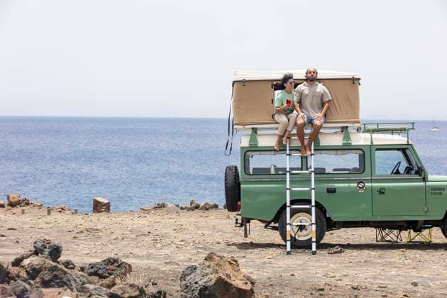 A blind man and a companion sit on the rooftop of a motorhome parked by the sea. They are enjoying the scenic view and feeling the breeze on a sunny day. Model Released JuanAizpuru_ID26099_752916_016 Copyright: xJuanxAizpurux