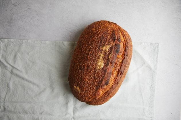 Top view of a freshly baked sourdough bread with a crispy crust, resting on a white linen cloth, offering a perfect example of traditional home baking. Model Released TwoInspirations_ID26492_764450_007 Copyright: xTwoxInspirationsx RECORD DATE NOT STATED