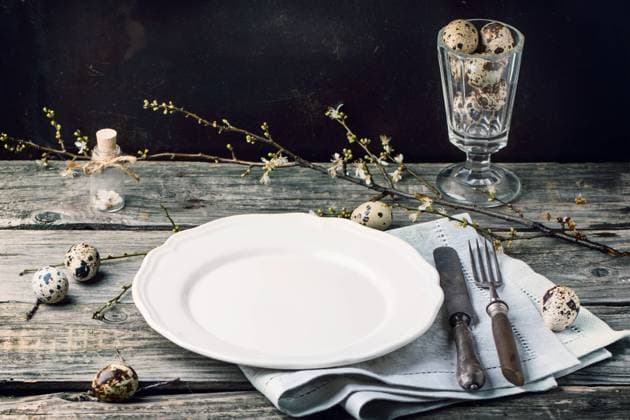 Gedeckter Ostertisch Easter table setting with vintage silverware, white plate, gray textile napkin, quail eggs and blossom branch on old wooden table Copyright: xZoonar.com NatáliexLarinax 22771634