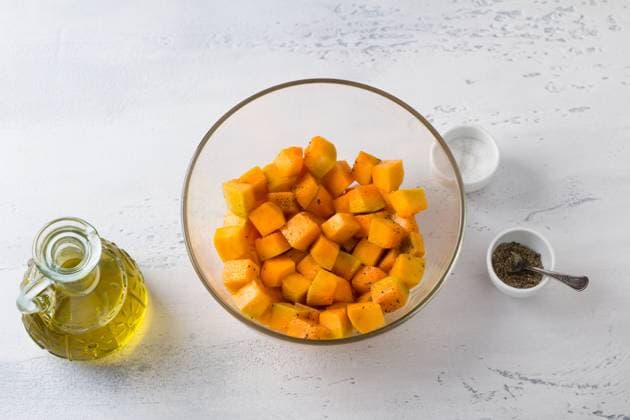 Glasschale mit Kürbiswürfeln, Olivenöl, Salz und Pfeffer auf einem hellblauen Tisch, Ansicht von oben. Kochen eines leckeren veganen Auflaufs Glass bowl with diced pumpkin, olive oil, salt and pepper on a light blue table, top view. Cooking delicious vegan casserole. Copyright: xZoonar.com OlgaxLepeshkinax 22777427