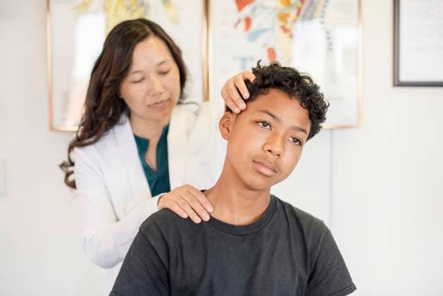 IMAGO Creative, Diversity, Pflege im Krankenhaus Doctor looking at young patients neck San Francisco, California, United States CR_HOOX250205-1586415-01 ,model released, Symbolfoto