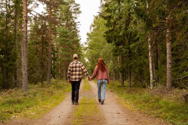 A couple walks down a serene forest path in Sweden, holding hands and enjoying nature. Tall trees surround them, creating a peaceful and romantic atmosphere. Model Released AlbaVitta_ID26447_763151_023 Copyright: xAlbaxVittax RECORD DATE NOT STATED