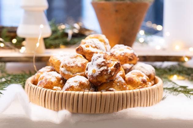 A basket filled with delicious pastries dusted with powdered sugar, set on a festive holiday table. The background is adorned with soft lights and greenery, creating a cozy atmosphere. Model Released HodeiUnzueta_ID26217_756320_007 Copyright: xHodeixUnzuetax RECORD DATE NOT STATED