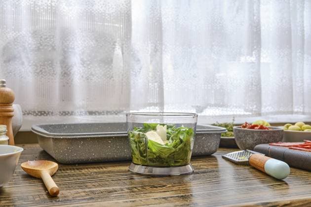 Helles Sonnenlicht fällt durch ein Fenster und beleuchtet eine Küchenarbeitsplatte, auf der frisches Gemüse geschnitten wird. Umliegende Schüsseln und Werkzeuge deuten darauf hin, dass die Zubereitung einer Mahlzeit im Gange ist Bright sunlight filters through a window illuminating a kitchen countertop where fresh vegetables are being chopped. Surrounding bowls and tools indicate meal preparation is underway Copyright: imageBROKER AlekseixIsachenko ibxaii12633019.jpg