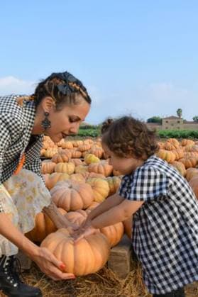 A Caucasian mother and son are standing outside a rural farm stand, smiling and looking at a selection of pumpkins 21770663 ,model released, Symbolfoto RECORD DATE NOT STATED