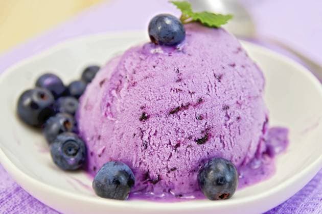 Heidelbeereis mit Minzblättern in einer Schale mit Beeren auf einem Hintergrund aus lila Stoff und Holzbrettern Blueberry ice cream with mint leaves in a bowl with berries on a background of purple cloth and wooden boards Copyright: imageBROKER kostrez ibxiqx12413061.jpg