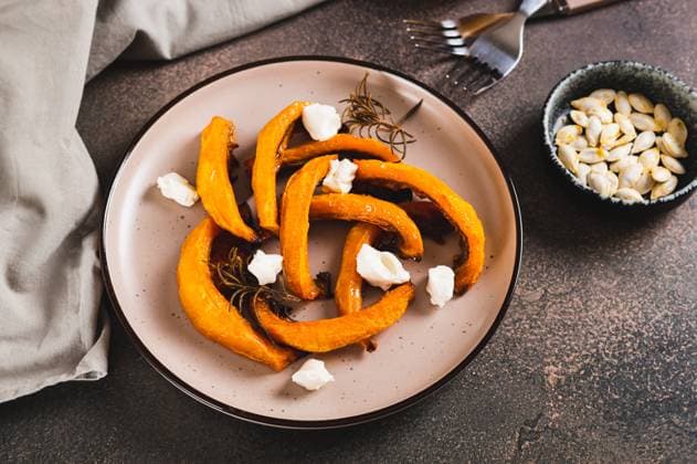 Appetitliche, mit Rosmarin gebackene Kürbisstücke auf einem Teller auf dem Tisch Appetizing pieces of sweet pumpkin baked with rosemary on a plate on the table Copyright: xZoonar.com ElenaxRuix 22810924