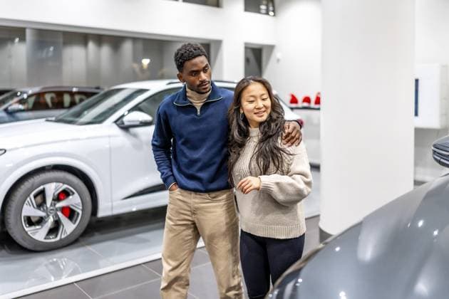 Ein glückliches multiethnisches Paar, das im Autohaus ein neues Elektroauto kauft, umarmt sich und wählt sein zukünftiges Fahrzeug Happy multiethnic couple buying a new electric car at the dealership, embracing and choosing their future vehicle Copyright: imageBROKER UnaixHuizi ibxuhu12460347.jpg ,model released, Symbolfoto ,property released